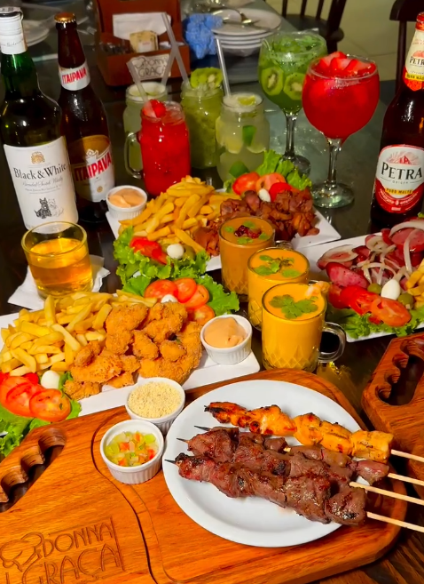 Mesa de happy hour com petiscos, espetinhos e bebidas da Donna Graça